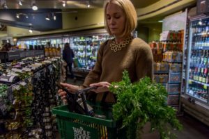 Woman looking at a bottle of wine while putting it in her Whole Foods basket