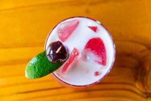 Top down view of an alcoholic beverage offered at Shingletown with a toothpick going through a lime and cherry