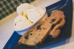Upclose of a chocolate chip cookie in a plate next to a bowl of vanilla ice cream at Zaw