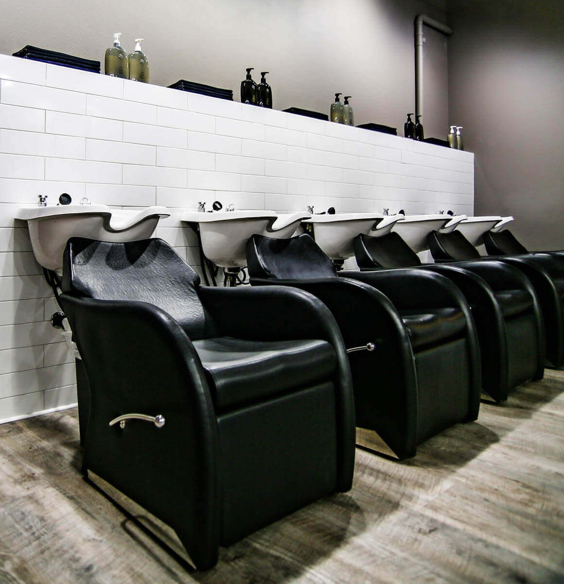 Line of black armchairs at Stan Parente Salon's washing stations