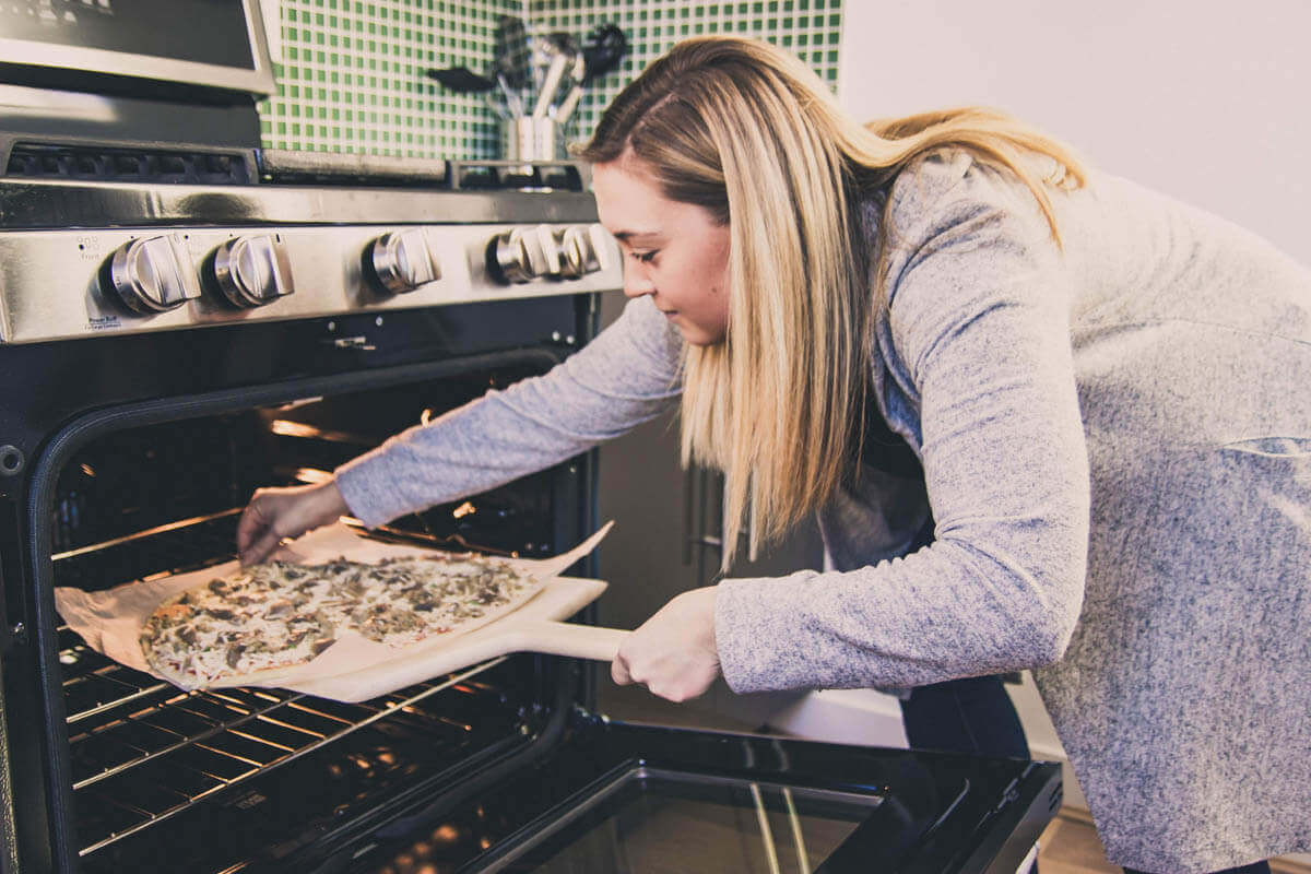 Female checks ZAW Pizza in oven