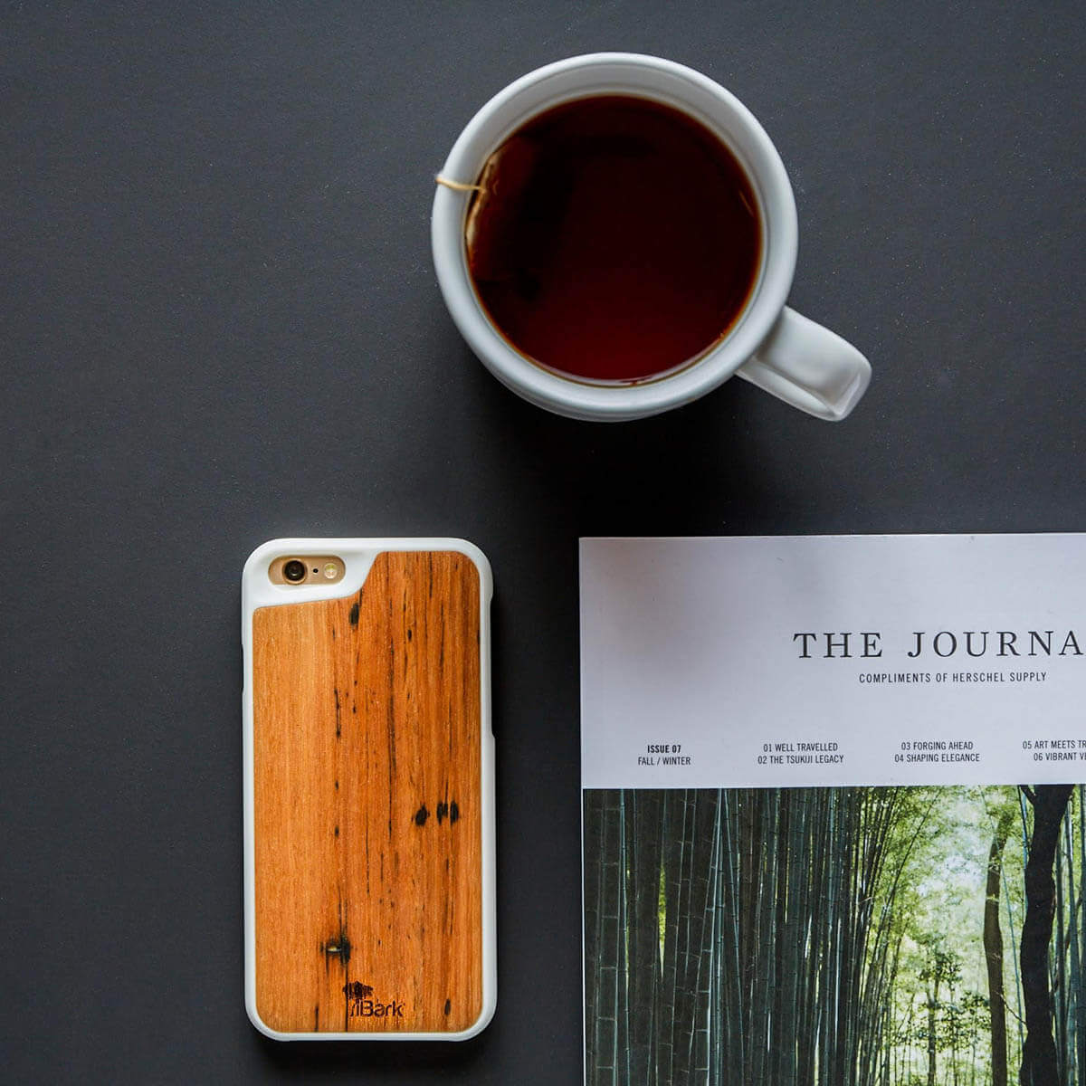 Cellphone with iBark wood cover on table with teacup and book