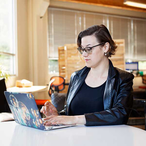 Female with glasses consults laptop
