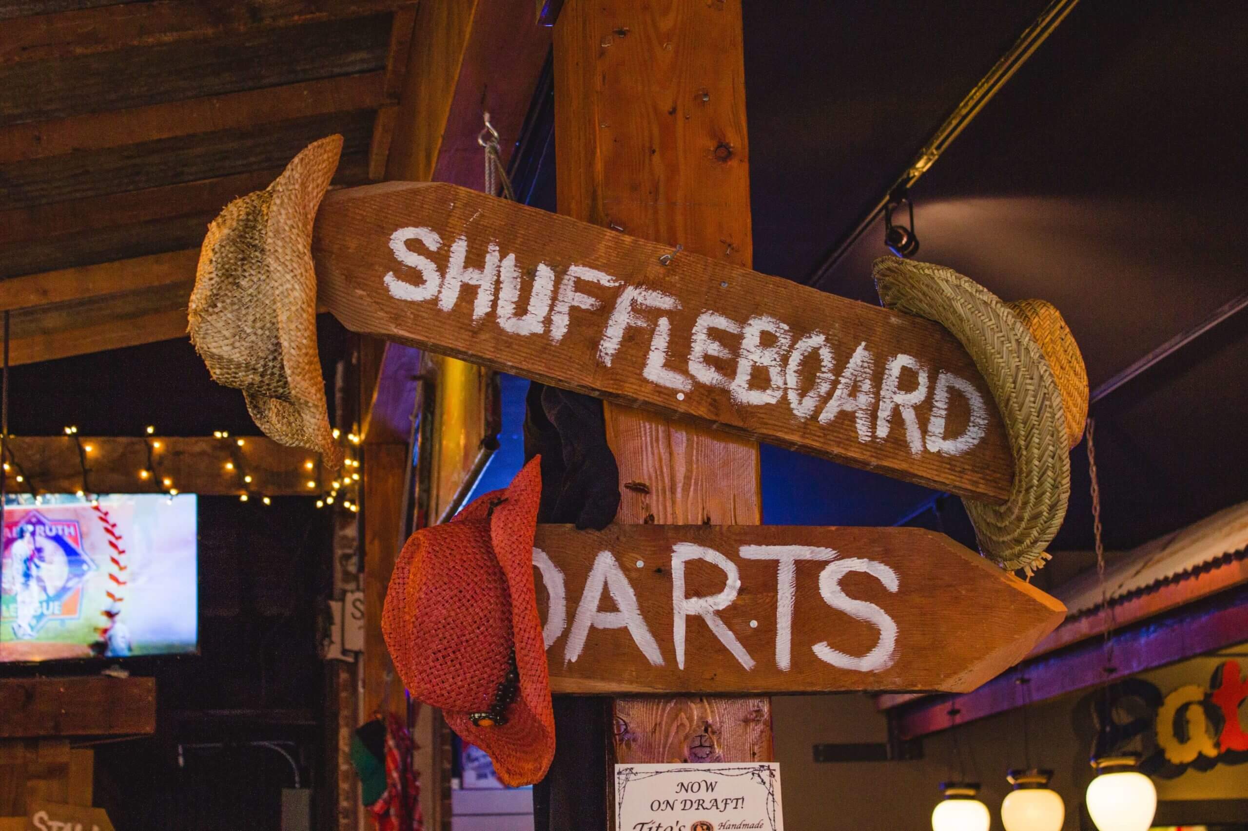 Shingletown wooden board signs pointing towards shuffleboard and darts