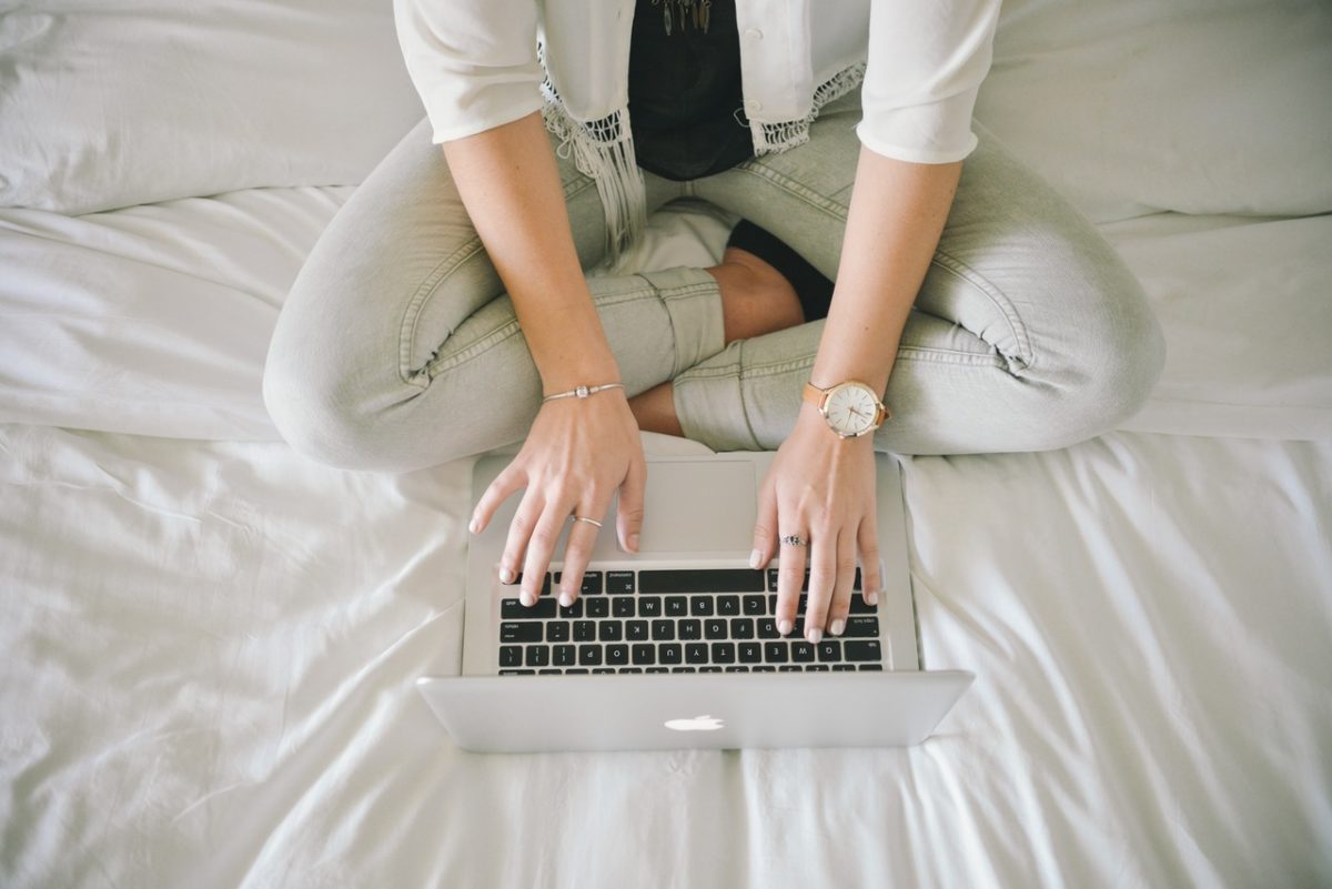 Woman sitting on her bed working on her laptop