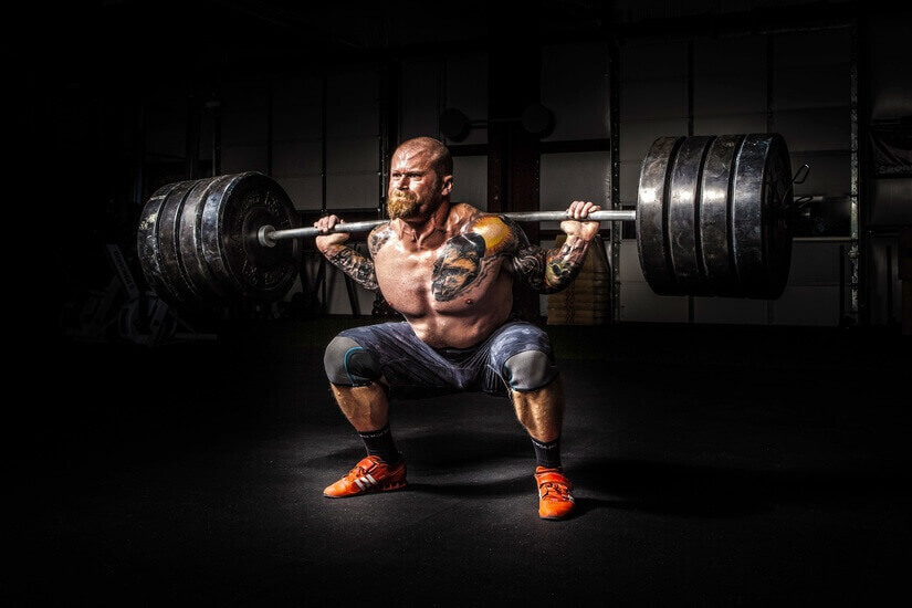 Strong tattooed man lifting a heavy weight from a dead squat