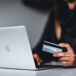 woman in front of laptop holding her credit card