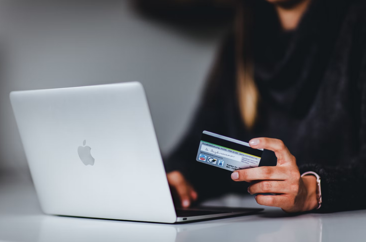 woman in front of laptop holding her credit card